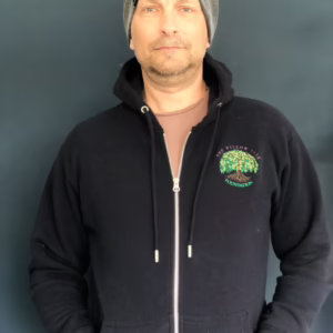 A man in a grey beanie and black hoodie with a "Willow Tree Foundation" logo looks calmly at the camera.